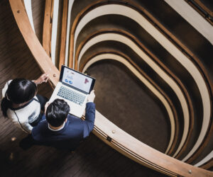 Two businesspeople at the top of a computer looking at data on a computer.